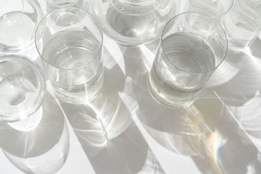 Sunlight falls at glasses of water on light background