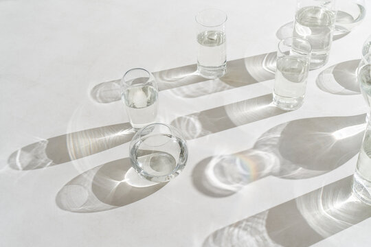 Sunlight falls at glasses of water on light background