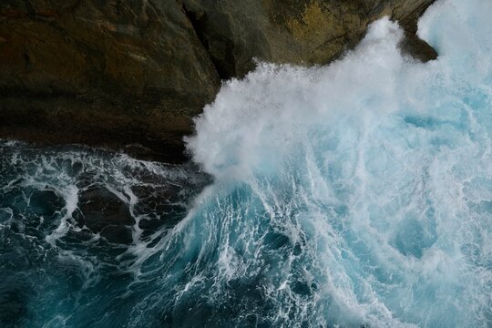 Aerial of a wave breaking against the cliffs
