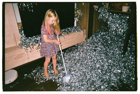 Girl in homemade dress sweeps the floor after a fun birthday party