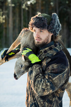 Hunter carrying dead deer on shoulder