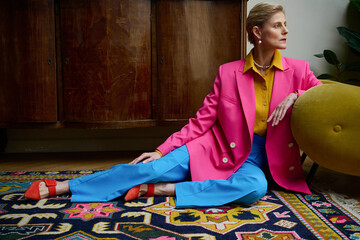Beautiful 50 year old woman in fashionable suit posing in the interior