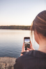 Woman taking picture of lake with cell mobile phone