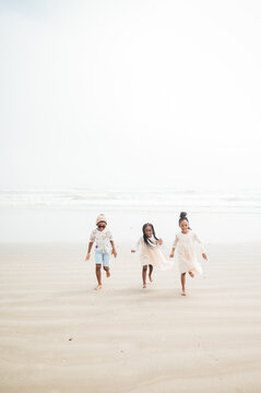 Siblings running on the beach on a foggy day