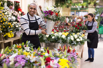 Fototapeta premium Male flower seller prepares a luxury bouquet at a flower shop