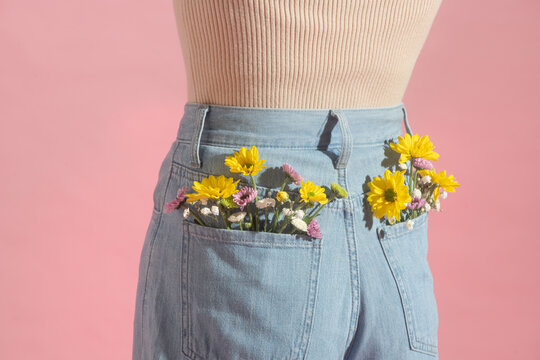 Woman with beautiful tender flowers in back pocket of jeans