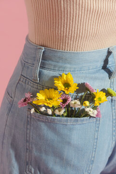 A small bouquet of yellow flowers in the back pocket of a light jeans
