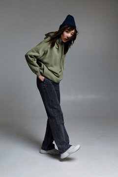Coll young Asian lady with hands in pockets in studio