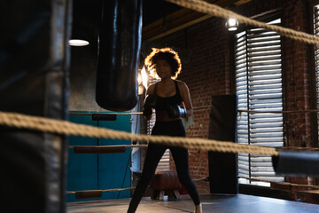 Women self defense girl power. African american woman fighter training punches on boxing ring. Healthy strong girl punching boxing bag. Training day in boxing gym. Strength fit body workout training