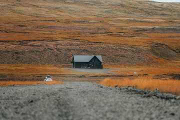 Black wooden lonely house against high mountain during golden fall 