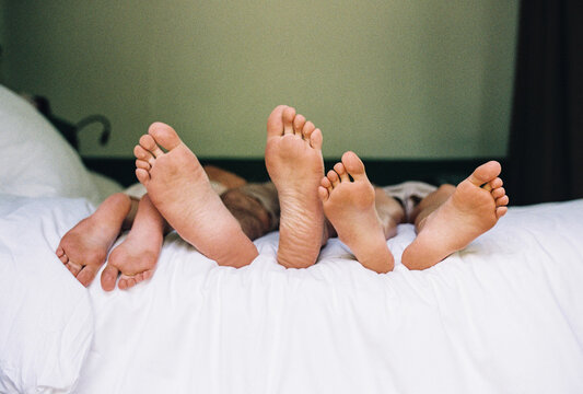 Adult and kids' feet on a bed