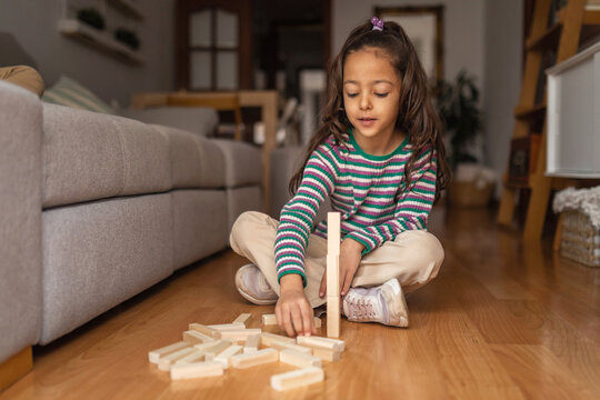 little girl playing with wooden blocks on the floor in the living 