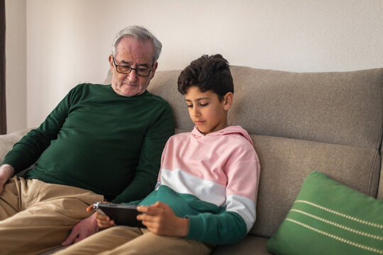 boy with his grandfather playing game console at home