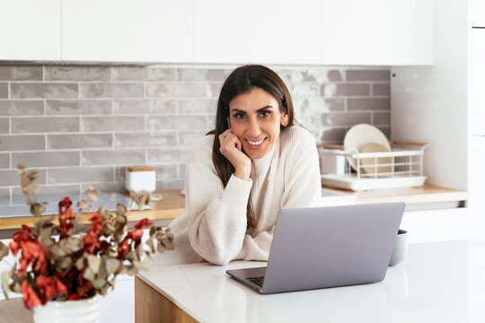 Positive woman in kitchen with computer