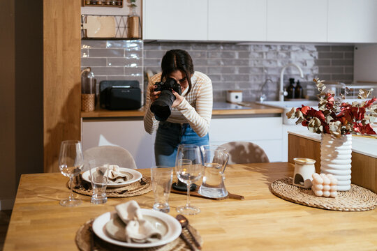 Woman photographing table setting in kitchen
