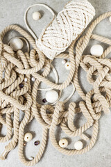 Messy rope and wooden beads spread over grey table.