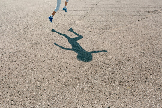 Child's legs and shadow silhouette hopping on pavement