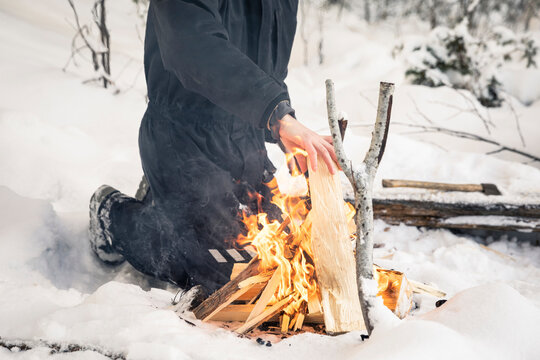 Man in snow maintaining camp fire