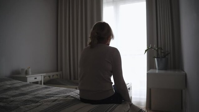 Mature woman sitting alone in the room, sad depressed person. Back view. mental health