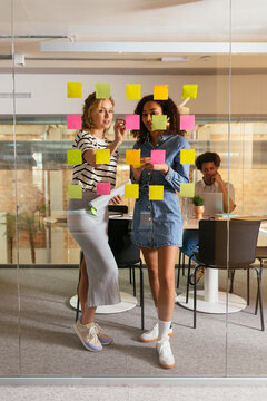 Business professionals brainstorming using adhesive notes in office