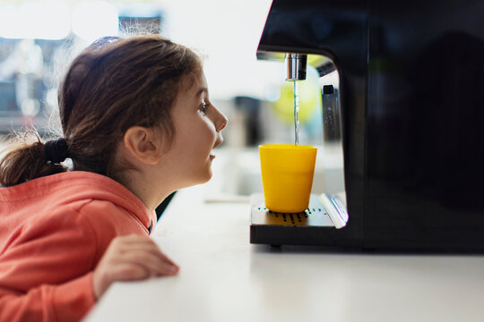 Cute kid pouring fresh water from filter machine