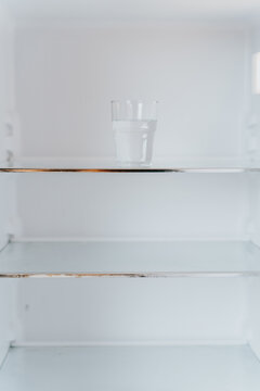 Empty fridge with a glass of water