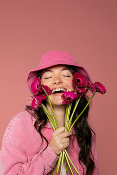 Studio portrait of woman in pink clothes holding fresh flowers