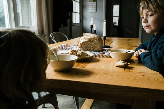 Two children sitting at dining table eating butternut squash soup 