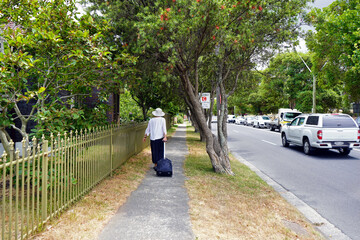 A woman walking in a sidewalk next to W Botany St in Sydney.