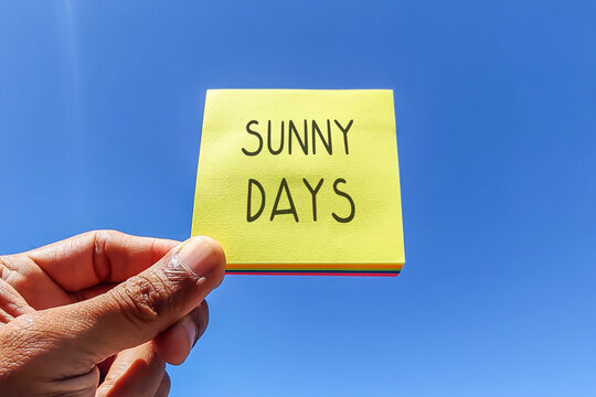 Sunny days. Text on yellow adhesive note with sky background.