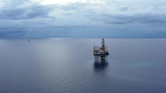 Jack up drilling rig and production platform in the middle of the ocean during couldy time
