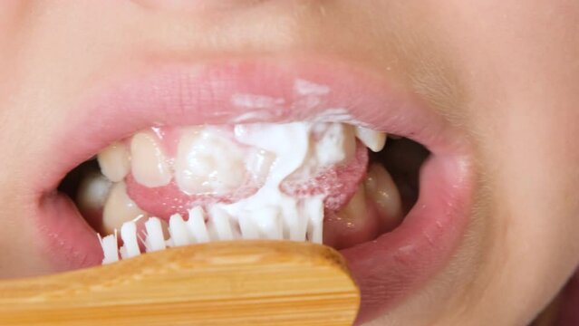 Child girl or teenage girl of eleven years old brush her teeth with eco toothbrush made of natural materials. Concept of dental hygiene, dental care and health.