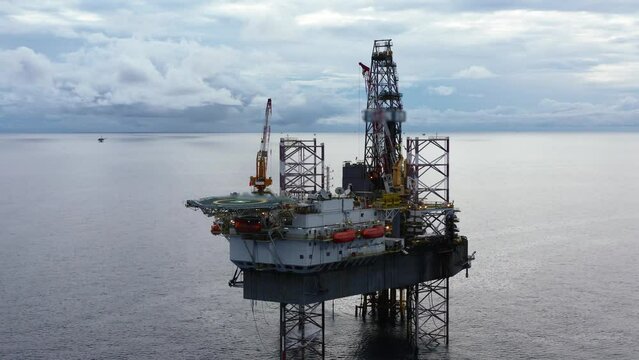 Jack up drilling rig and production platform in the middle of the ocean during couldy time
