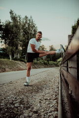 Athlete performing leg stretching exercises after a run in a natural environment. Fitness themed photograph showcasing physical activity flexibility and health.