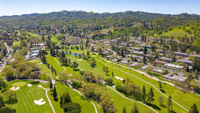 A stunning drone photo captures the Rossmoor community's picturesque beauty, showcasing homes, a golf course, green hills, and a clear blue sky.