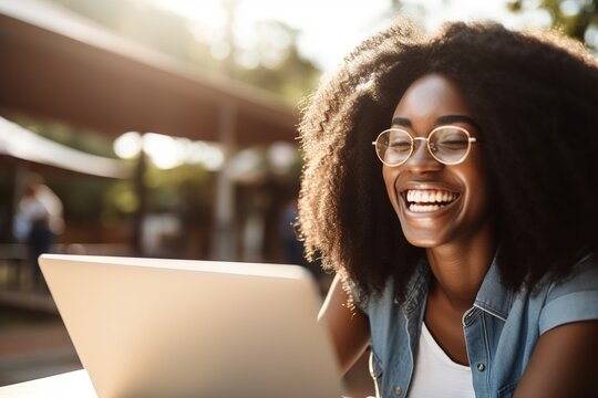 Smiling african american woman having online video call on laptop while sitting outdoor. Generative ai