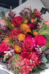 Pink, red and orange roses with green grass in a bouquet in red tones