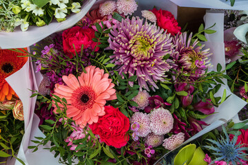 Pink, red and orange chrysanthemums and gerberas with green eucalyptus in a bouquet in red tones