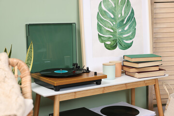 Stylish turntable with vinyl record on console table in room