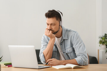 Man in headphones studying on laptop at home. Online translation course