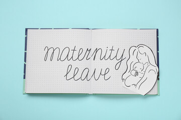 Notebook with phrase Maternity Leave, paper cutout of mother and child on light blue background, top view