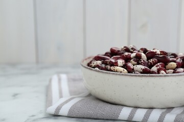 Bowl with dry kidney beans on table, closeup. Space for text