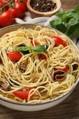 Delicious pasta with anchovies, tomatoes and spices on wooden table