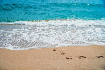 Emerald sea foam and footprints in the sand