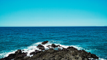 Blue sky and summer sea with rocky wave foam