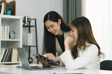 Two professional millennial Asian startup businesspeople are discussing evaluation data in a conference room, focusing on growth and pointing to a financial account chart,graph.