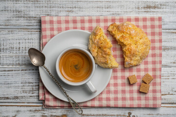 White porcelain coffee cup with saucer and lemon cookies on a wooden table, closeup, top view. Hot...