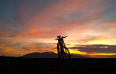 Silhouette of mountain bike by the beach with dramatic sunrise background.