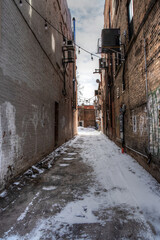 snow covered alley way between two brick buildings