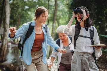 Fotobehang woman family walking in the forest to watching a bird in nature, using binocular for birding by looking on a tree, adventure travel activity in outdoor trekking lifestyle, searching wildlife in jungle © chokniti